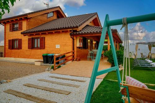 a house with a swing and a playground at Madera y Miel Casa Rural con niños en Puy du Fou in Guadamur