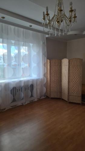 a room with white curtains and a chandelier at Колливинг на Республике (золотой квадрат) in Astana