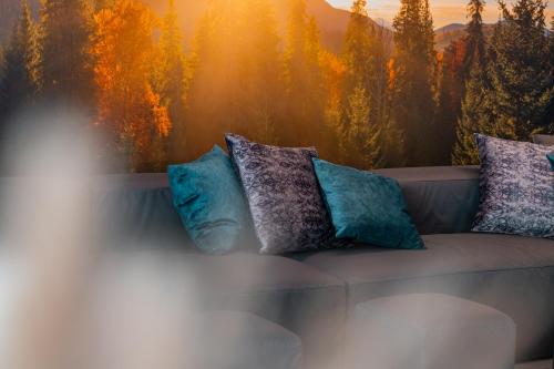 a couch with pillows sitting in front of a window at Berg & SPA Hotel Urslauerhof in Maria Alm am Steinernen Meer