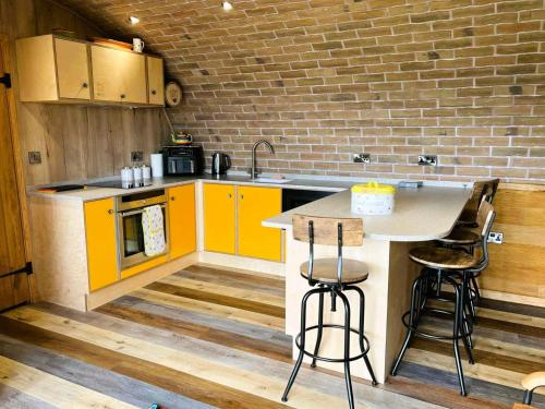 a kitchen with yellow cabinets and a counter with stools at Honeybee Home in Llansantffraid-ym-Mechain