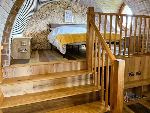 a bedroom with a bed in a room with a staircase at Honeybee Home in Llansantffraid-ym-Mechain