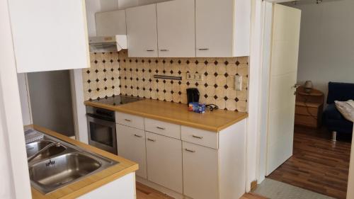 a kitchen with white cabinets and a sink at Villa Theresa Apartments in Mainburg