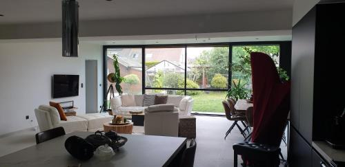a living room with white furniture and a large window at Privé kamer met eigen douche en lavabo in Bruges