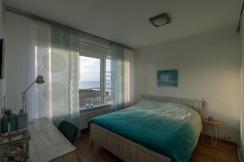 a bedroom with a bed and a large window at Appartement Majelle in Egmond aan Zee