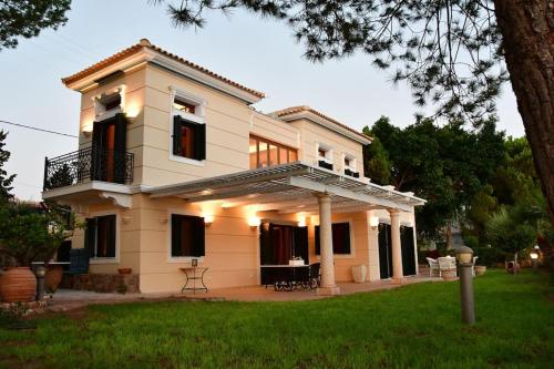 a white house with a balcony and a yard at Villa Althea in Perdika