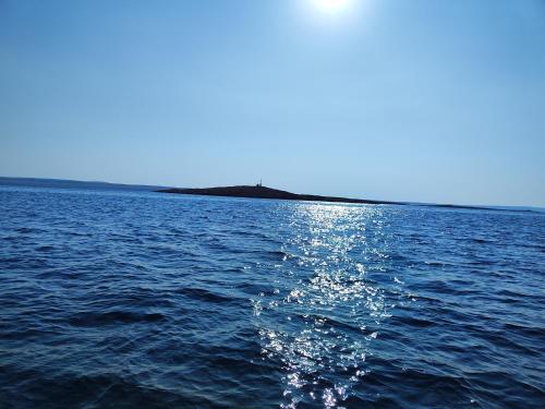 un cuerpo de agua con el sol reflejándose en el agua en VILLA APARTMENTS FILIP en Starigrad-Paklenica