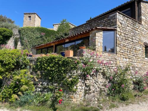 une maison en pierre avec des fleurs sur un mur en pierre dans l'établissement Les Colombes Vegan, à Aubres