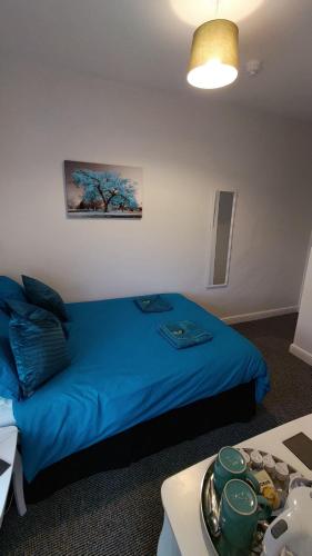 a bedroom with a blue bed and a table at The Castleton in Blackpool