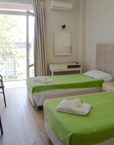 a room with two beds with green sheets and a window at City Center Hotel in Kalamata