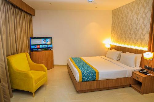 a hotel room with a bed and a yellow chair at Hotel Sky Sierra Wayanad in Kalpetta