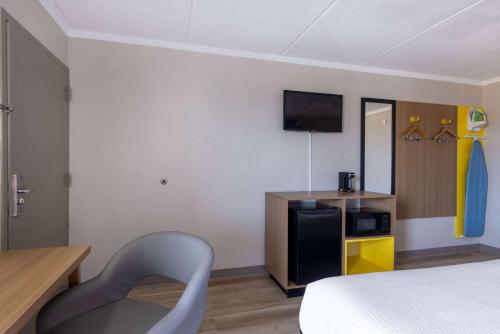 a hotel room with a bed and a chair at Days Inn & Suites by Wyndham Fort Bragg/Cross Creek Mall in Fayetteville