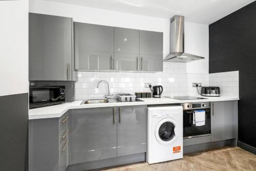 a kitchen with a sink and a washing machine at Sleek and Stylish Converted 1Bed in Old Boiler Factory - Flat 4 in Nottingham