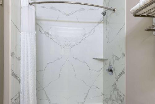 a bathroom with a shower with a white marble wall at Days Inn & Suites by Wyndham Fort Bragg/Cross Creek Mall in Fayetteville
