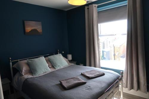 a bedroom with a bed with blue walls and a window at Stylish Margate apartment in Margate