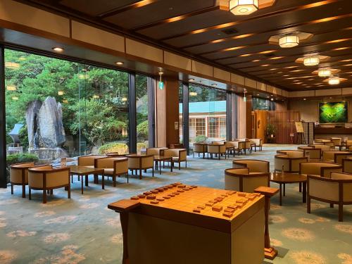 restauracja ze stołami i krzesłami oraz dużym oknem w obiekcie Takinoyu Hotel w mieście Tendo