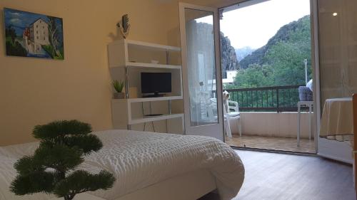 - une chambre avec un lit et un balcon avec une télévision dans l'établissement Studio Amèlie les bains, à Amélie-les-Bains-Palalda