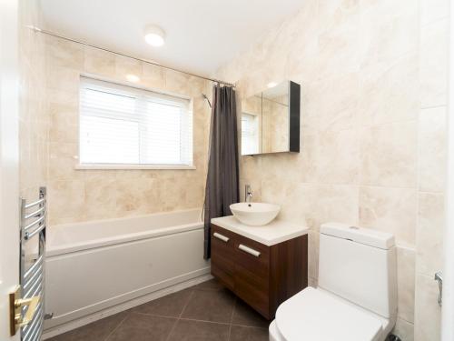 a bathroom with a sink and a toilet and a tub at Pass the Keys Stylish Apt in quiet cul de sac in Surbiton