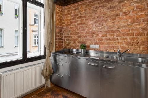 uma cozinha com um lavatório de aço inoxidável e uma parede de tijolos em Castello Apartments em Viena