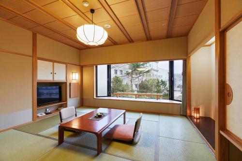 a living room with a table and a large window at Takinoyu Hotel in Tendo