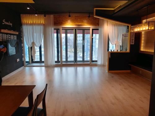 een grote kamer met een houten vloer en ramen bij T stay pension in Cheongju