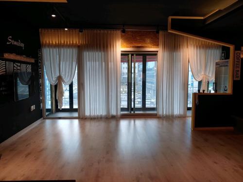 a living room with white curtains and a wooden floor at T stay pension in Cheongju