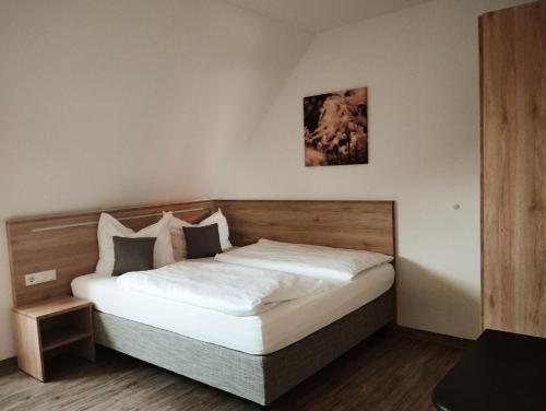 a bedroom with a large bed with white sheets at Gasthaus zur Linde in Dombühl