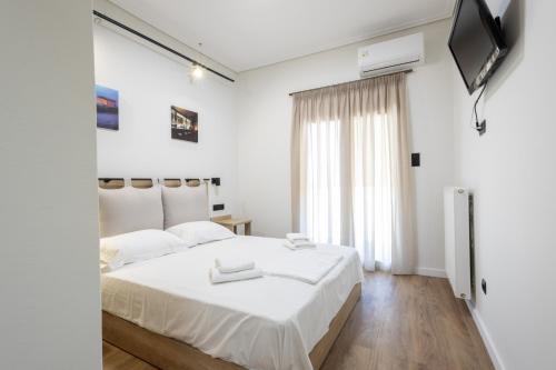 een witte slaapkamer met een groot bed en een televisie bij Acropolis Oasis Modern 2 bdrm apt Steps Away from History in Athene