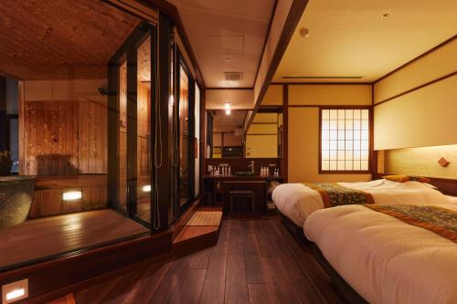 a hotel room with two beds and a desk at Takinoyu Hotel in Tendo