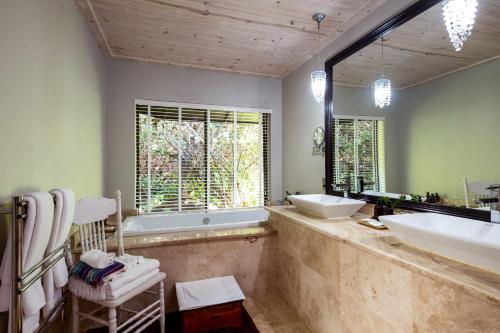 La salle de bains est pourvue d'une baignoire, d'un lavabo et d'un miroir. dans l'établissement Prana Lodge, à Chintsa