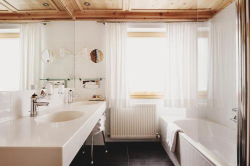 a bathroom with a sink and a bathtub and a tubermott at Burg Hotel Oberlech in Lech am Arlberg