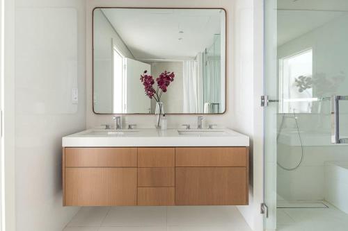 a bathroom with a sink with a mirror and a vase of flowers at Frank Porter - Al Saadiyat Island in Abu Dhabi