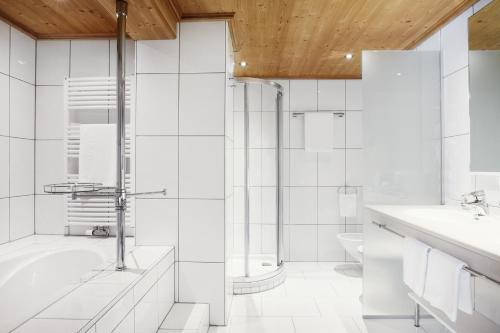 a white bathroom with a shower and a toilet at Burg Hotel Oberlech in Lech am Arlberg