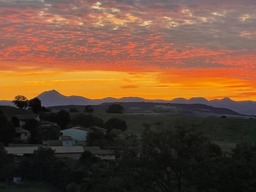 um pôr-do-sol sobre uma cidade com montanhas ao fundo em Perle de vue em Glaine-Montaigut