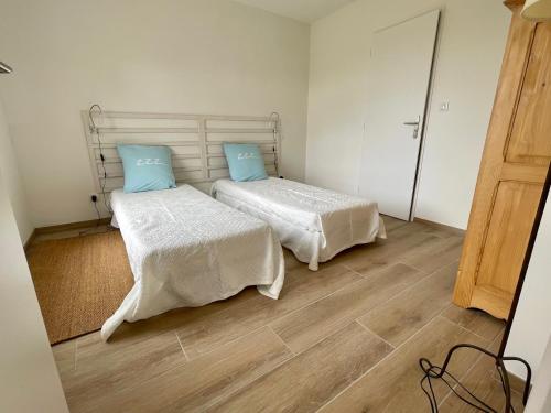 um quarto com 2 camas com lençóis brancos e almofadas azuis em Perle de vue em Glaine-Montaigut