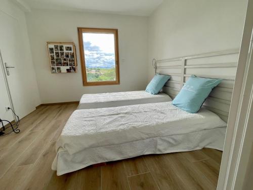 two beds in a room with a window at Perle de vue in Glaine-Montaigut
