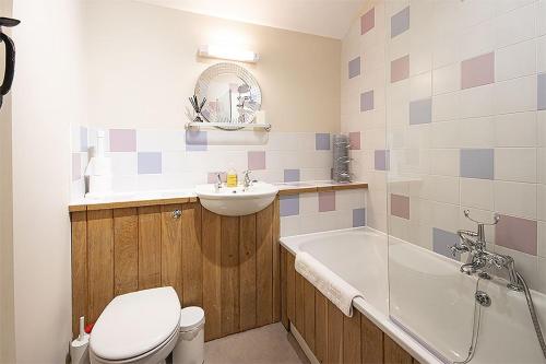a bathroom with a toilet and a sink and a tub at Mill Village 81, Trout Cottage in Somerford Keynes