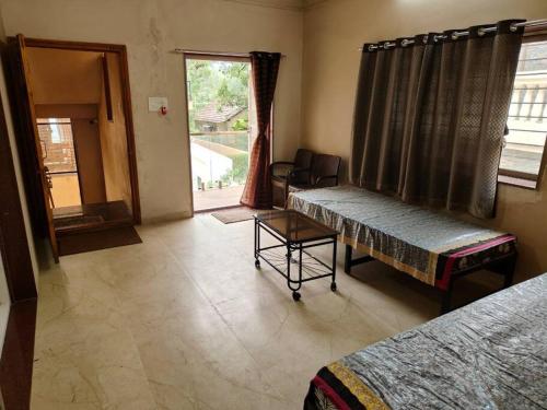 een kamer met 2 bedden, een tafel en een raam bij Suite with valley view Panhala Fort in Panhāla