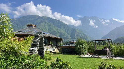 坎格拉的住宿－Osho Himalayas Wellness Resort，坐在房子前椅子上的女人