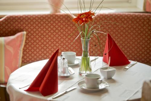 a white table with red napkins and a vase with flowers at Hotel Bären in Rottweil