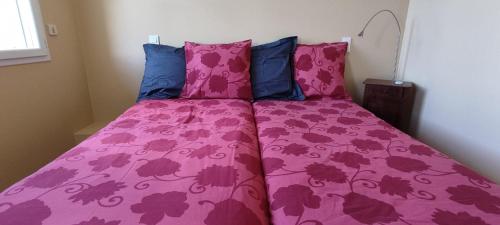 Cama rosa con sábanas moradas y almohadas azules en Appartement République, en Carbonne