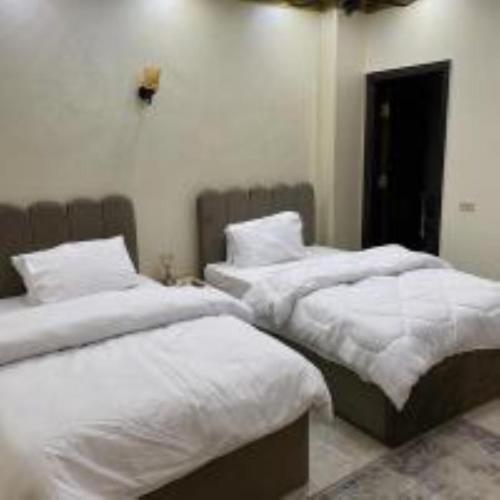 two beds in a bedroom with white sheets and pillows at Crystal pyramid inn in Cairo