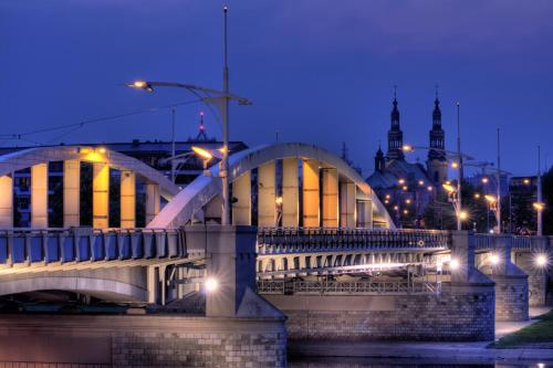 a bridge over a river with a city in the background at Apartamenty Browar Luxury Old Town Poznań 24h in Poznań