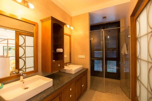a bathroom with two sinks and a glass shower at StayVista at Villa Arcadia with Alfresco Dining in Candolim