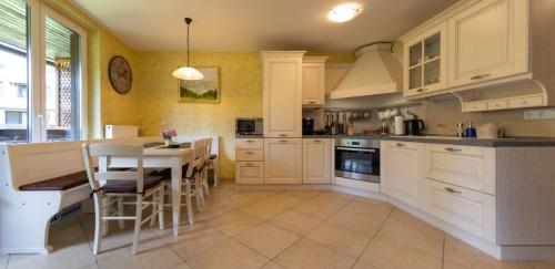 a kitchen with white cabinets and a table and chairs at Apartma Krvavec - cosy mountain retreat in Cerklje na Gorenjskem