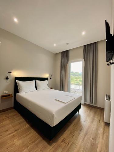 a bedroom with a large bed and a large window at Merly Hotel in Përmet