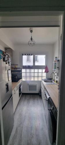 une cuisine avec des appareils blancs et un parquet dans l'établissement Appart hypercentre Château-Thierry aux portes de Paris et de la Champagne, à Château-Thierry