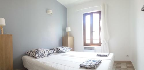 a white bedroom with a bed and a window at Location saisonnière dans le cœur historique – T3 pour 4 à 6 personnes in La Ciotat