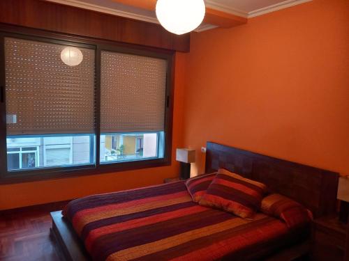 um quarto com paredes cor-de-laranja, uma cama e 2 janelas em RIOBO´S HOUSE em Vigo