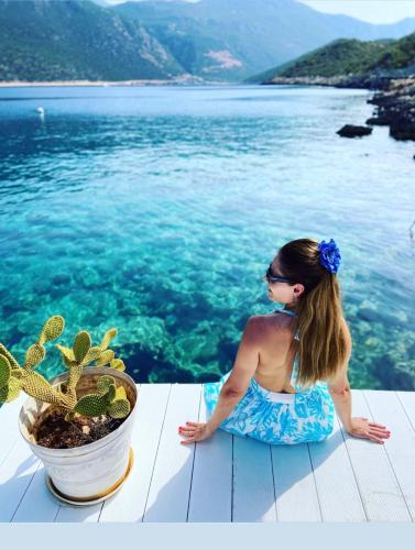 a woman sitting on a table next to the water at Club Çapa Hotel in Kas