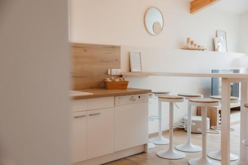 una cocina con armarios blancos, mesa y taburetes en Chaleureux appartement 8 couchages #4, en Embrun